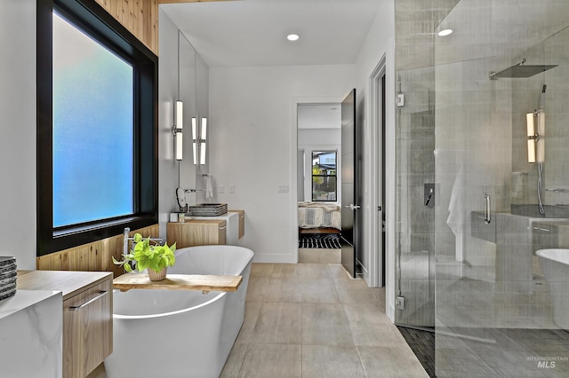 ensuite bathroom with connected bathroom, a shower stall, baseboards, tile patterned floors, and a soaking tub