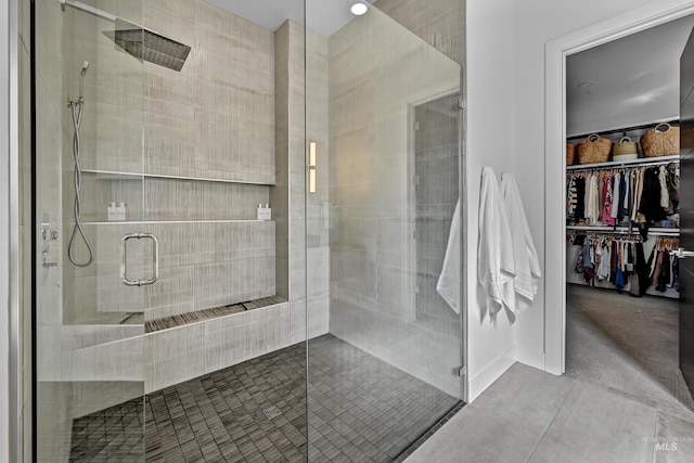 bathroom with tile patterned flooring, a stall shower, and a walk in closet