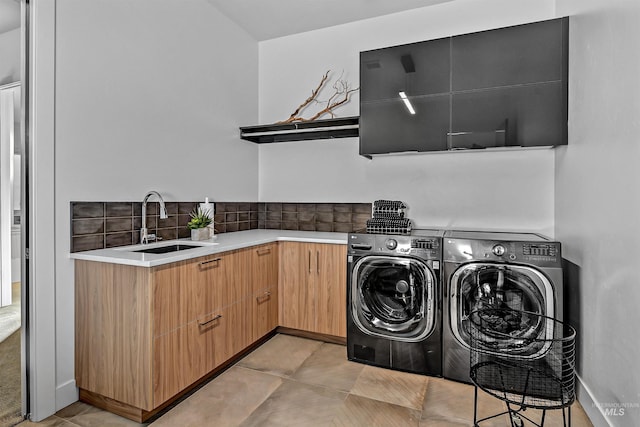 laundry area featuring cabinet space, light tile patterned flooring, washing machine and dryer, and a sink