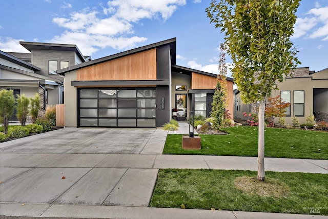 contemporary home with an attached garage, concrete driveway, and a front lawn