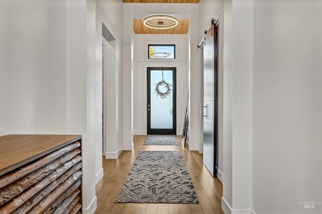 doorway featuring a barn door, baseboards, and light wood-style floors