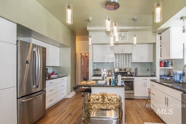 kitchen with decorative light fixtures, a center island, white cabinets, and appliances with stainless steel finishes