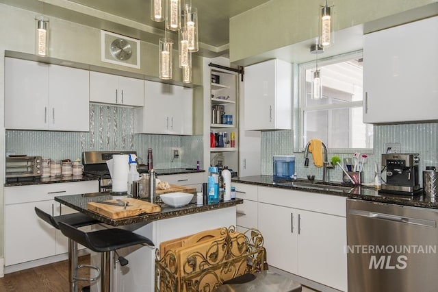 kitchen featuring white cabinetry, sink, stainless steel appliances, and a kitchen bar