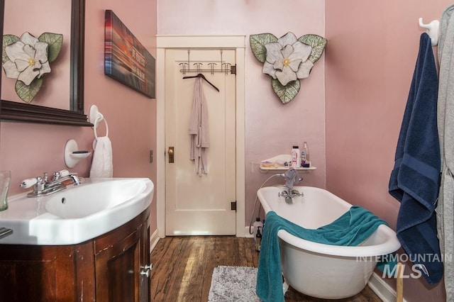 bathroom with hardwood / wood-style flooring, vanity, and a bath