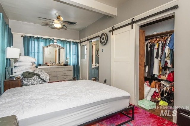 bedroom with ceiling fan, a barn door, and a closet