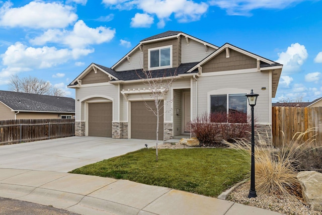 craftsman-style home with a front yard, fence, roof with shingles, concrete driveway, and stone siding