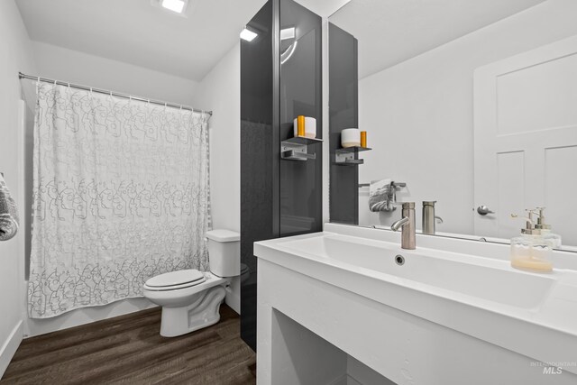 bathroom with shower / tub combo, toilet, wood finished floors, and vanity