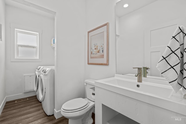 bathroom with visible vents, baseboards, toilet, wood finished floors, and washer and dryer