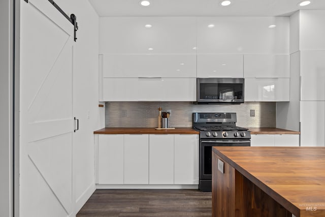 kitchen featuring butcher block counters, decorative backsplash, appliances with stainless steel finishes, white cabinets, and modern cabinets