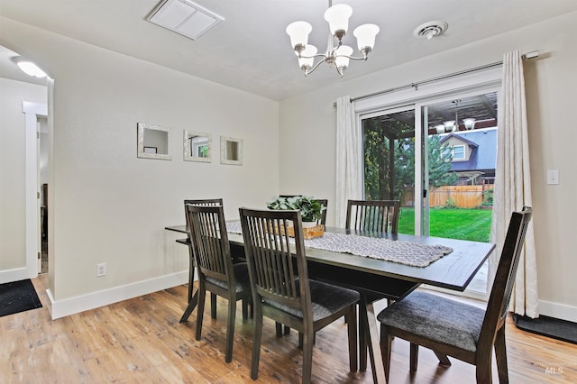 dining space featuring hardwood / wood-style flooring and an inviting chandelier