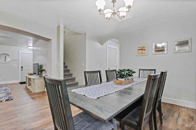 dining space featuring wood-type flooring and an inviting chandelier