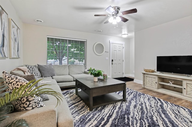 living room with ceiling fan and dark wood-type flooring