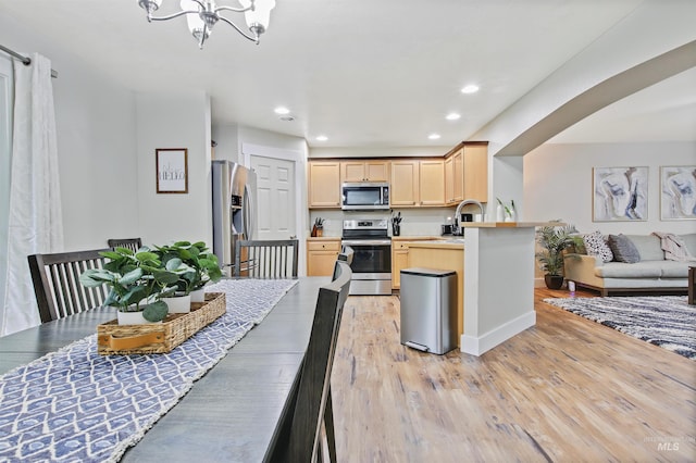 dining space featuring sink, a chandelier, and light wood-type flooring