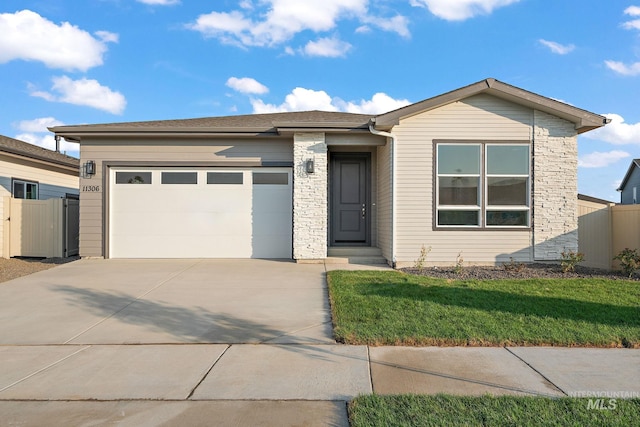 view of front of home featuring stone siding, concrete driveway, an attached garage, and fence