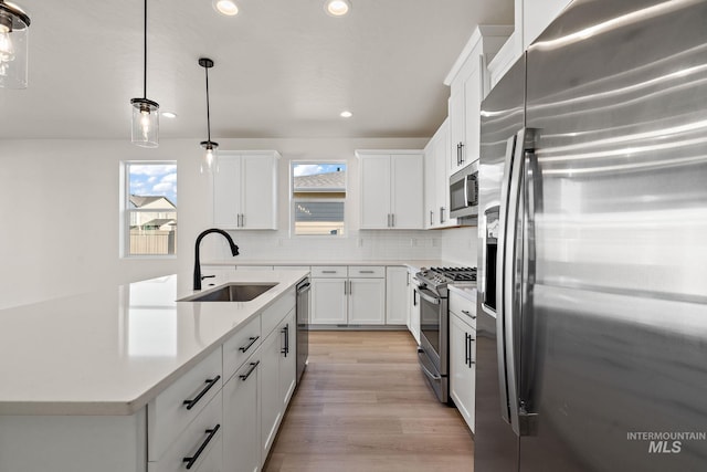 kitchen featuring a sink, decorative backsplash, light countertops, white cabinets, and appliances with stainless steel finishes