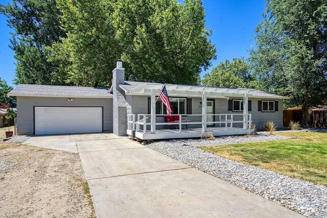 ranch-style home featuring covered porch, a front yard, and a garage