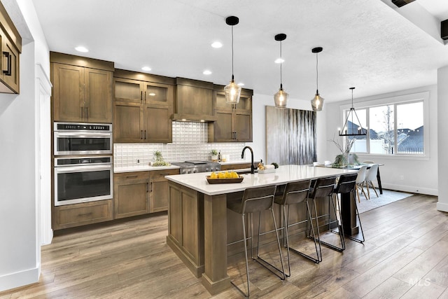 2493 E Galleon Ln, Meridian, ID 83642 - kitchen with stainless steel double oven, custom range hood, baseboards, light countertops, and light wood-style flooring