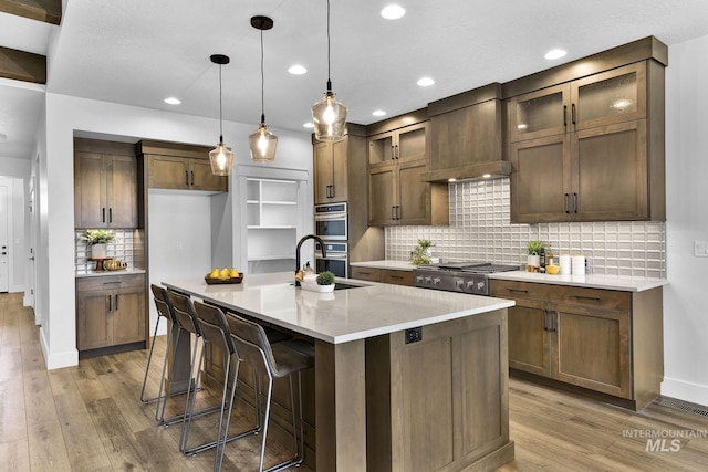 2493 E Galleon Ln, Meridian, ID 83642 - kitchen with a sink, stainless steel appliances, light wood finished floors, decorative backsplash, and light countertops