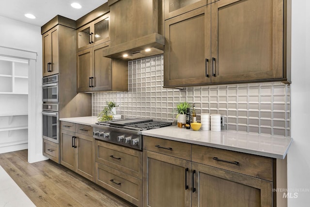 2493 E Galleon Ln, Meridian, ID 83642 - kitchen featuring appliances with stainless steel finishes, custom range hood, tasteful backsplash, light wood finished floors, and recessed lighting