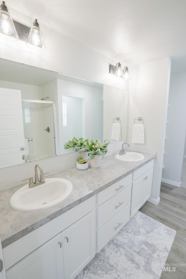 6073 W Mikonos St, Meridian, ID 83646 - bathroom featuring a shower stall, double vanity, and wood finished floors