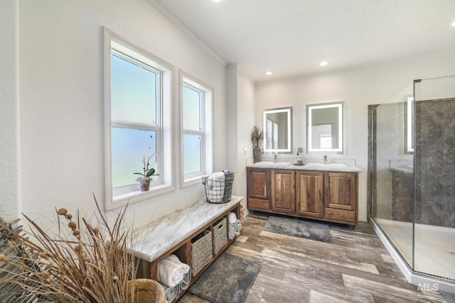 bathroom with recessed lighting, wood finished floors, a sink, double vanity, and a stall shower