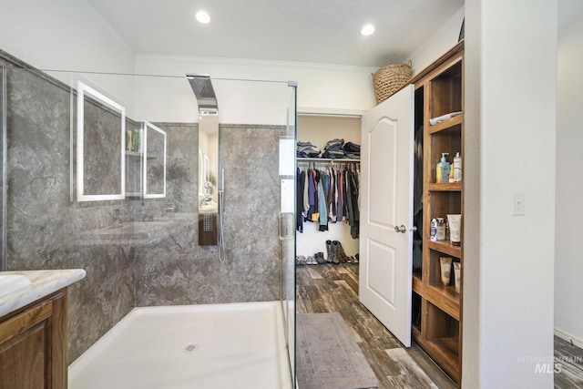 bathroom with a stall shower, ornamental molding, wood finished floors, a spacious closet, and vanity