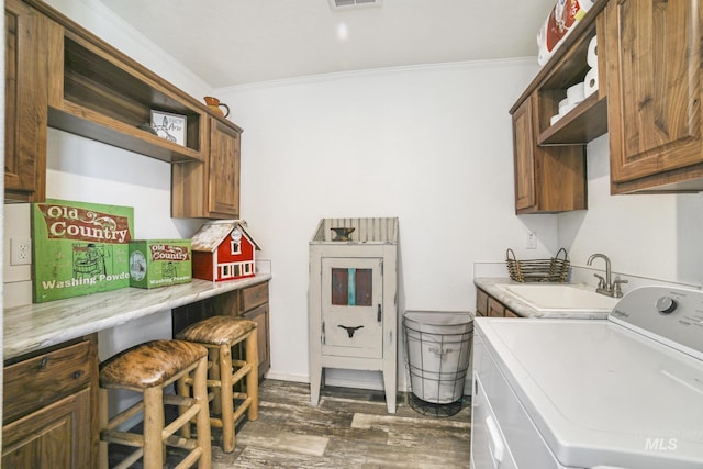 laundry room featuring dark wood-style floors, crown molding, cabinet space, a sink, and washer / dryer