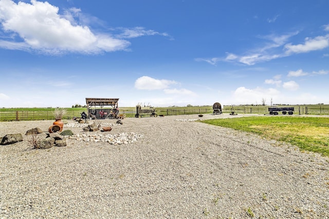 view of street with gravel driveway, a rural view, and an enclosed area