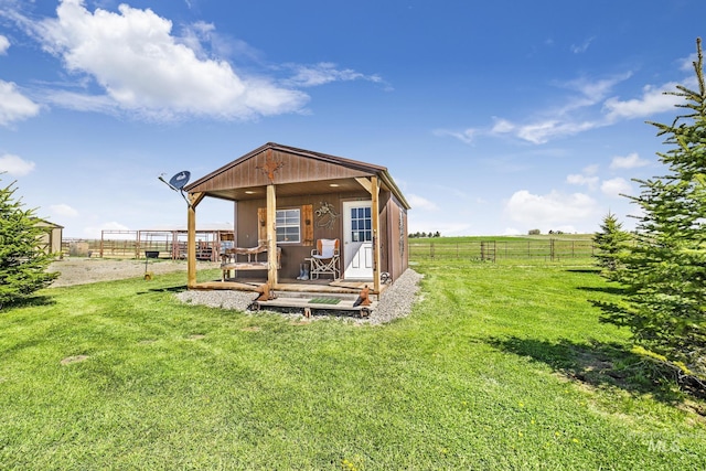 back of house with an outbuilding, a yard, a rural view, and fence