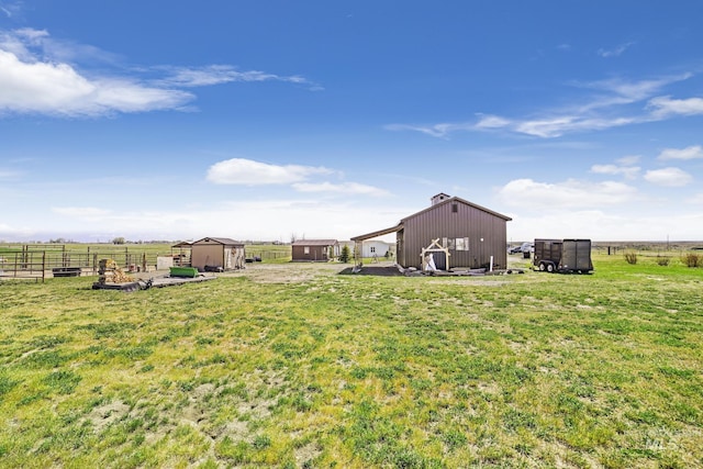 view of yard with fence, a pole building, an outbuilding, and a rural view