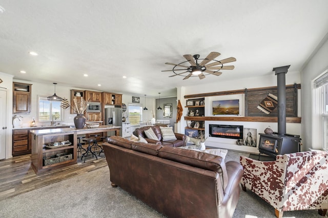 living area featuring a wood stove, ceiling fan, dark wood-style flooring, and recessed lighting