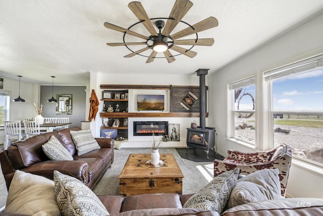 carpeted living area with a ceiling fan and a wood stove