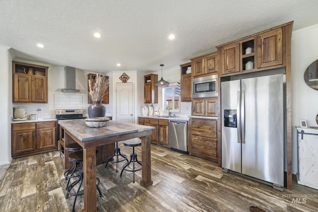 kitchen with dark wood-style floors, pendant lighting, open shelves, stainless steel appliances, and wall chimney exhaust hood