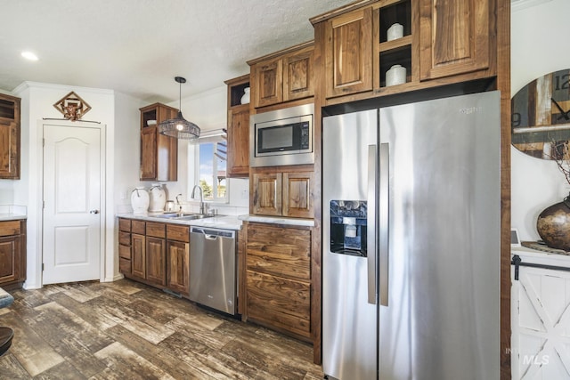 kitchen with a sink, light countertops, appliances with stainless steel finishes, hanging light fixtures, and dark wood finished floors