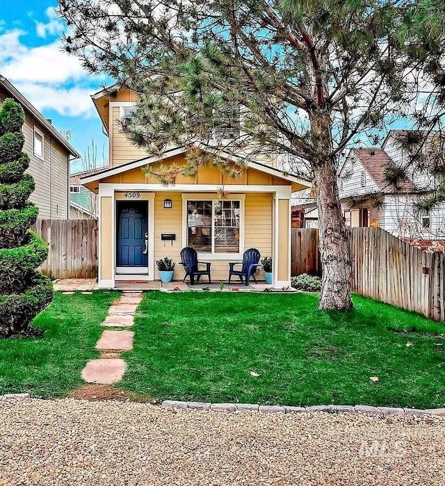 rear view of house featuring fence, a yard, and a porch