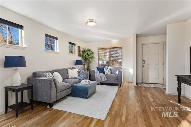 living room with baseboards, light wood-style flooring, and a wealth of natural light
