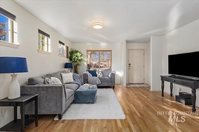 living room with baseboards, a wealth of natural light, and light wood-style flooring