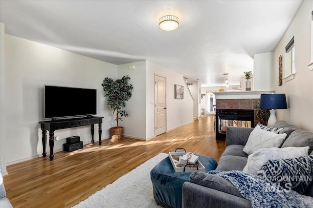 living room with baseboards, wood finished floors, and a tile fireplace