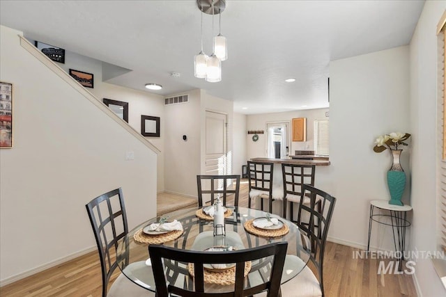 dining area with stairway, baseboards, light wood-style flooring, and visible vents