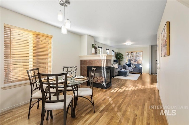 dining area featuring baseboards, a fireplace, and wood finished floors