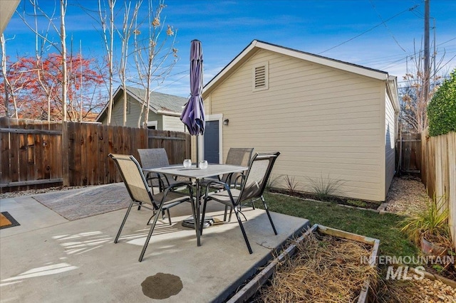 exterior space with outdoor dining area, a fenced backyard, and a garage