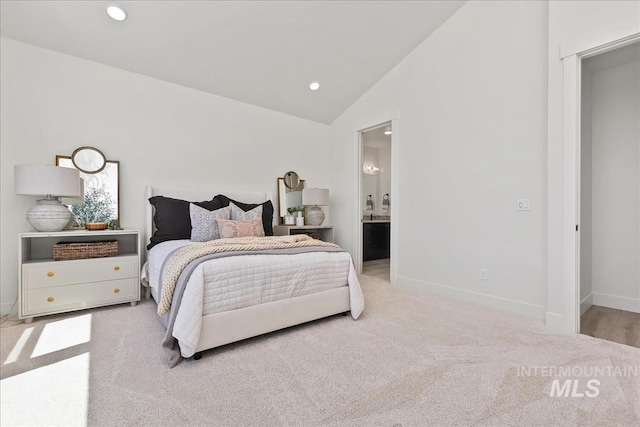 carpeted bedroom featuring vaulted ceiling and ensuite bath