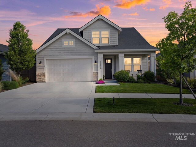 craftsman-style house featuring concrete driveway, a front yard, stone siding, an attached garage, and a porch
