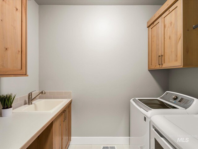 washroom featuring separate washer and dryer, cabinet space, and baseboards