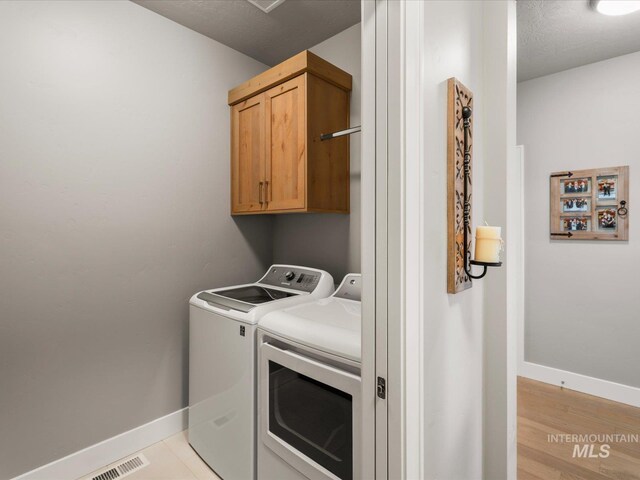 laundry area with cabinet space, independent washer and dryer, baseboards, and light wood-style floors