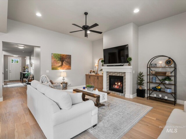 living area featuring a ceiling fan, baseboards, a fireplace, light wood-style flooring, and recessed lighting