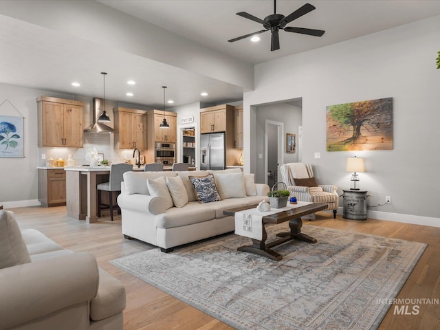 living room featuring baseboards, a ceiling fan, light wood finished floors, and recessed lighting