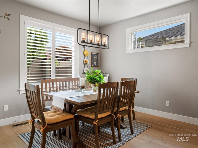 dining area with wood finished floors, a chandelier, and baseboards