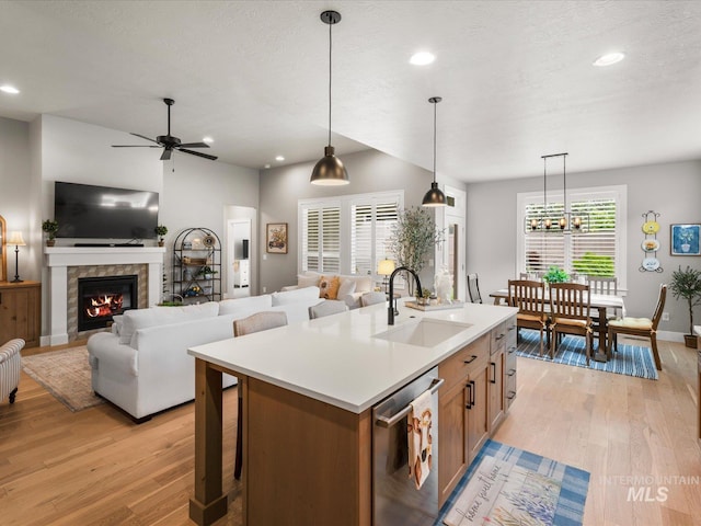 kitchen featuring a sink, light wood finished floors, dishwasher, brown cabinets, and recessed lighting