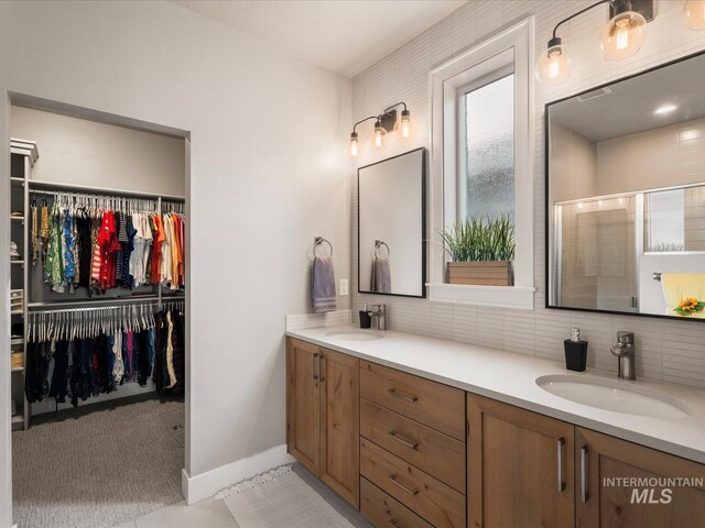 full bath featuring double vanity, a shower stall, a walk in closet, tasteful backsplash, and baseboards